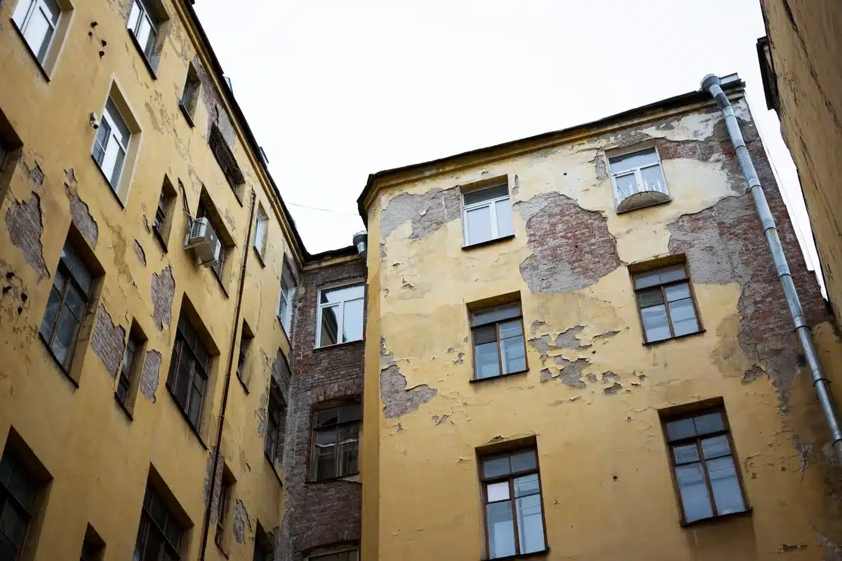 Dettagli di una facciata di edificio in cattivo stato di manutenzione con elementi danneggiati