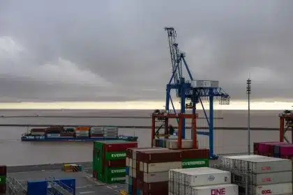 Terminale portuale con container e navi cargo al tramonto, simbolo della strategia di trasporto marittimo