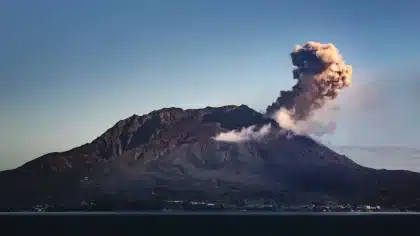 Colata lavica su pendici vulcaniche con pennacchio di cenere in risalita