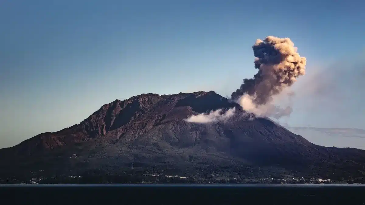 Colata lavica su pendici vulcaniche con pennacchio di cenere in risalita