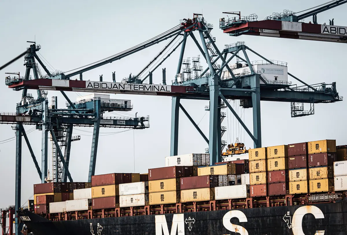 Terminal portuale con gru che movimentano container in una giornata operativa