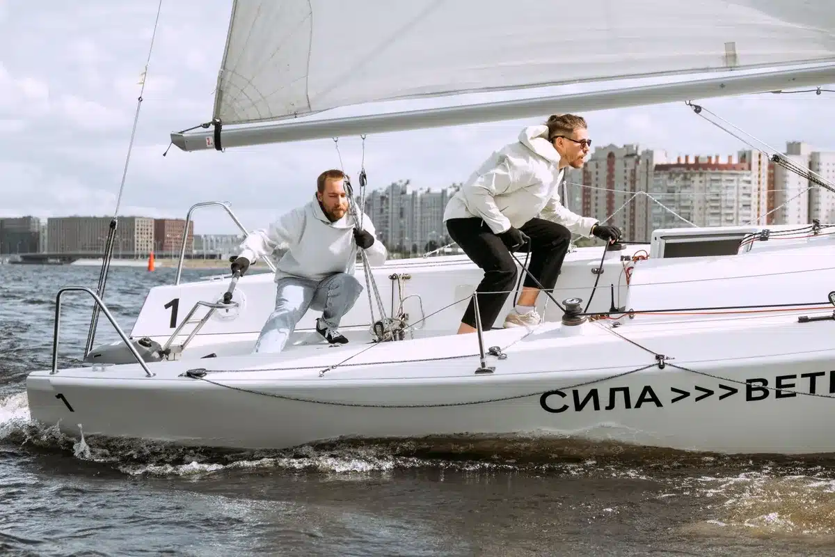 Gruppo di persone in barca a vela che collaborano alle manovre in porto