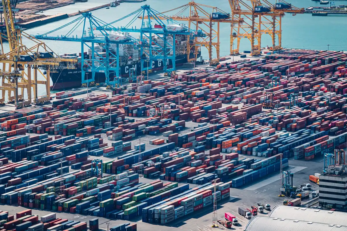 Porto container con gru e figure anonime che esaminano documenti su una scrivania durante un'indagine antitrust
