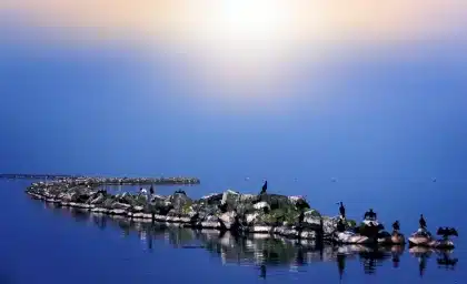 Terrazza di un santuario al tramonto con pellegrini in silhouette e una candela