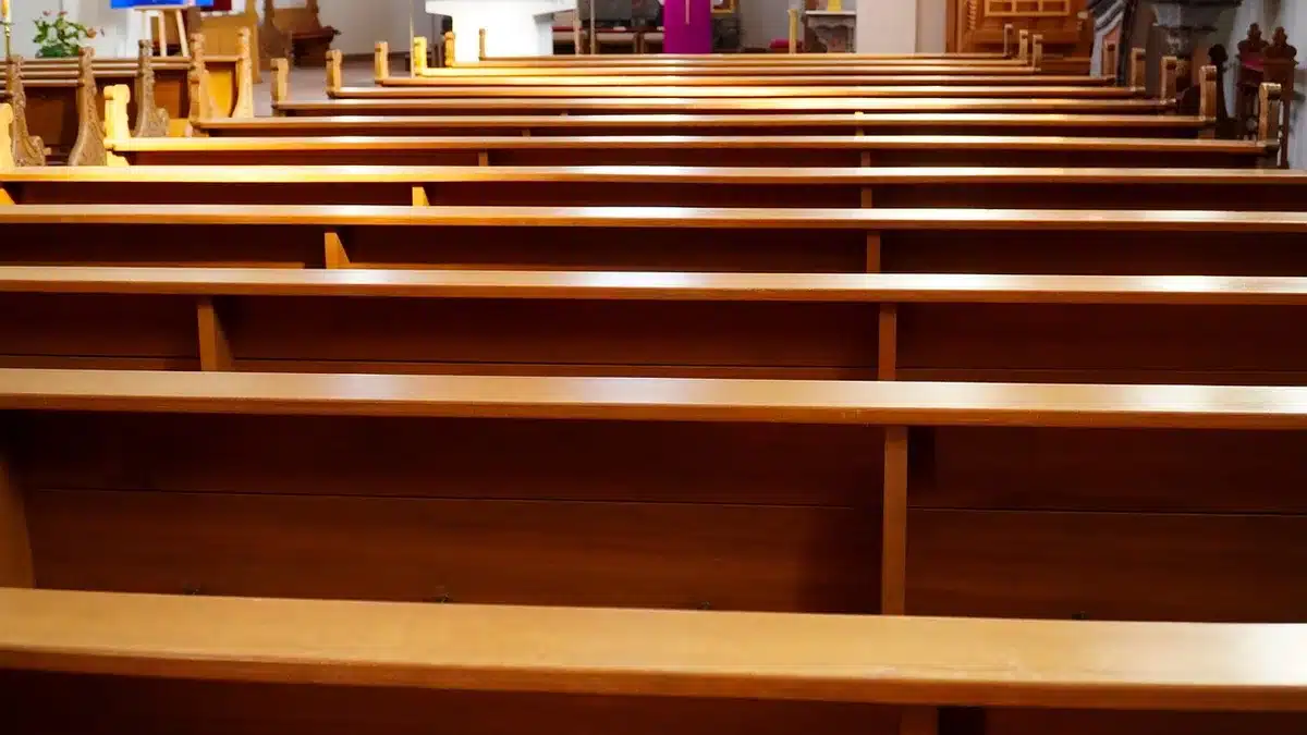Interno di una chiesa con banchi vuoti e luce che entra dalle vetrate