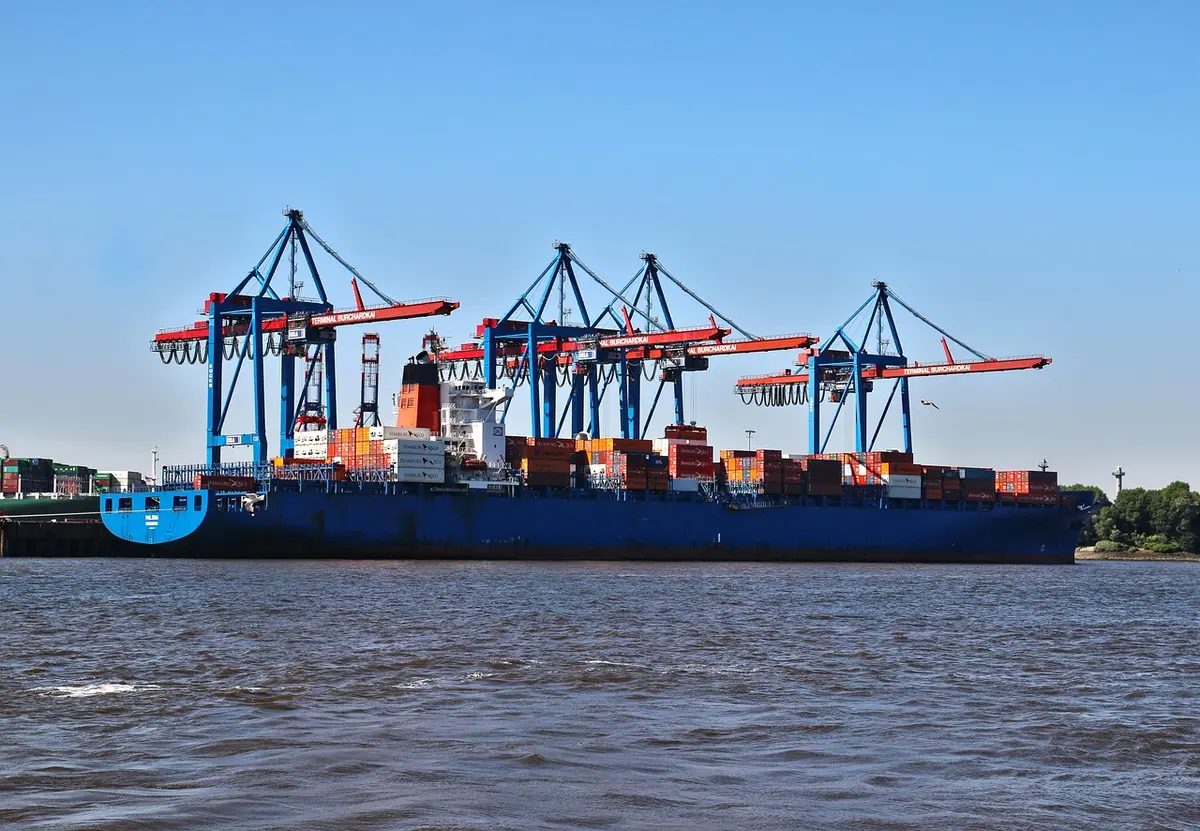 Terminal container con gru, pile di container e mezzo di movimentazione in movimento