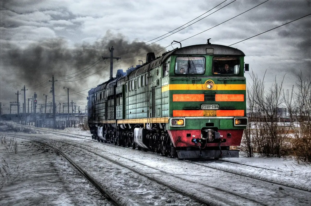 Linee ferroviarie multiple con carri merci e operai in lontananza, vista panoramica