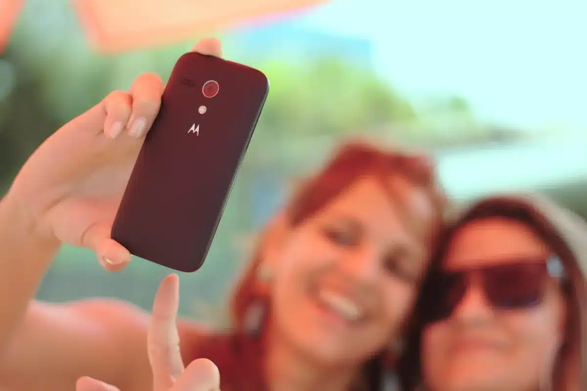 Smartphone con app di pagamento digitale in mano sopra il timone di una barca, con il mare sullo sfondo