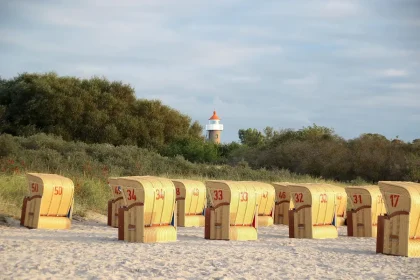 Tender anonimo vicino a una isola barriera con dune e un faro sullo sfondo