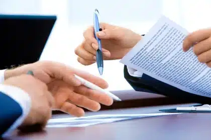 Mani anonime che scambiano buste e documenti su un tavolo d'ufficio