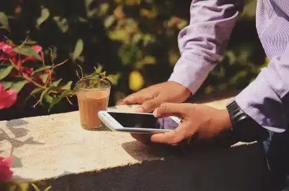 Mani che scorrendo uno smartphone vicino a documenti e una facciata comunale sfocata