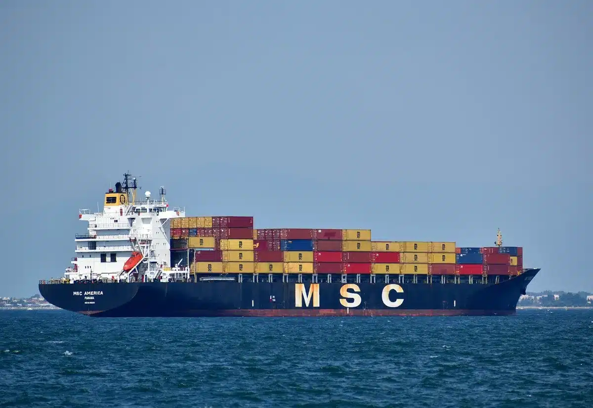 Nave mercantile in mare mosso vicino a un porto, simbolo di rischi e interruzioni