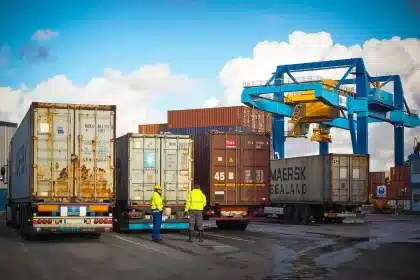 Banchina portuale con gru container e operai in controluce, scena anonima