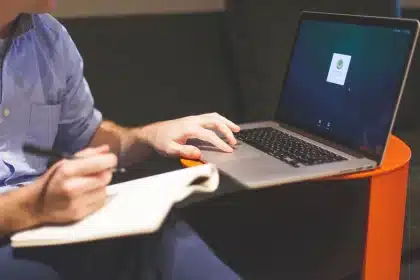 Persona anonima che digita su un portatile con diagramma testuale e note