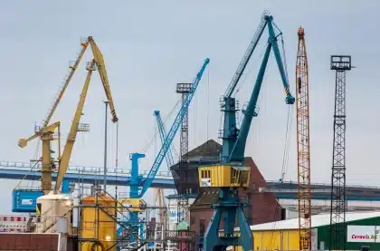 Banchina portuale con gru e scafo di portacontainer all'orizzonte