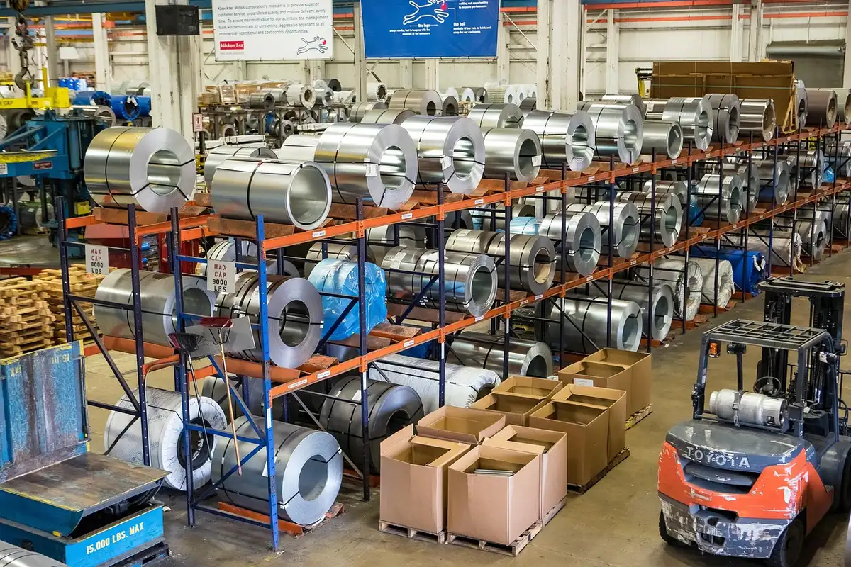 Silhouette di lavoratori in magazzino con pallet e furgone davanti a un hub logistico